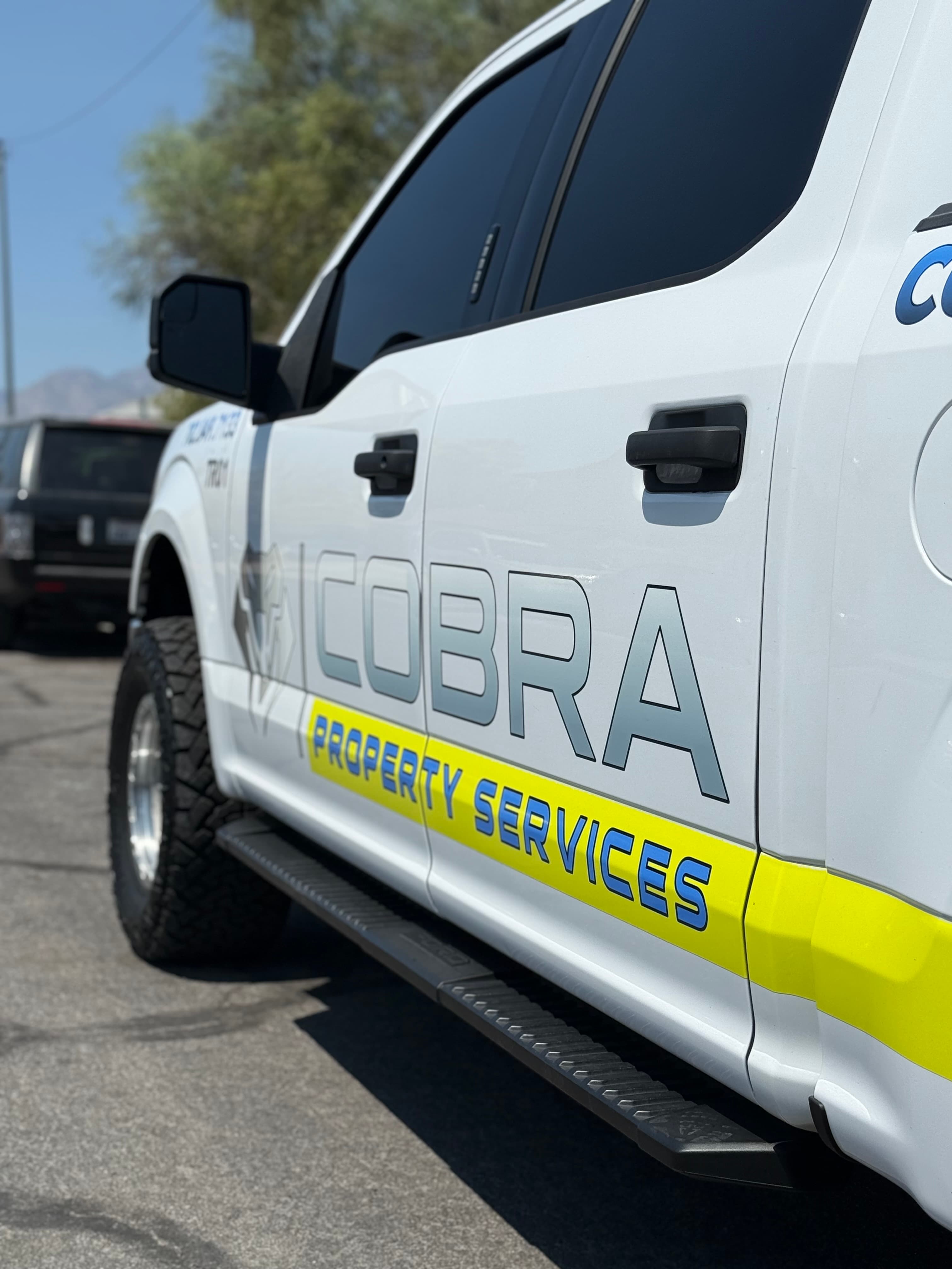 White service truck with Cobra Property Services logo and a yellow stripe along the side.